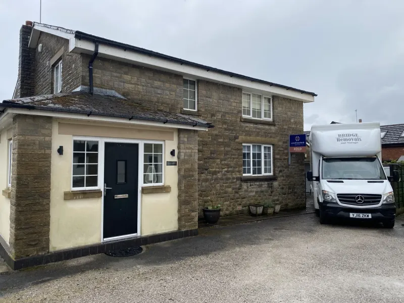 Bridge Removals van outside a stone house in Heywood, a Cowell Norford SOLD board in view, on a house removals job.