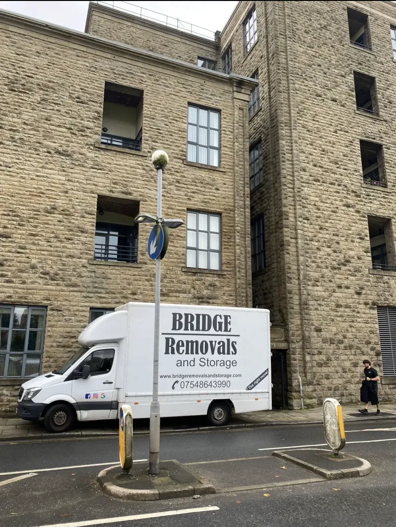 Bridge Removals van below a converted stone mill building on a house removals job.