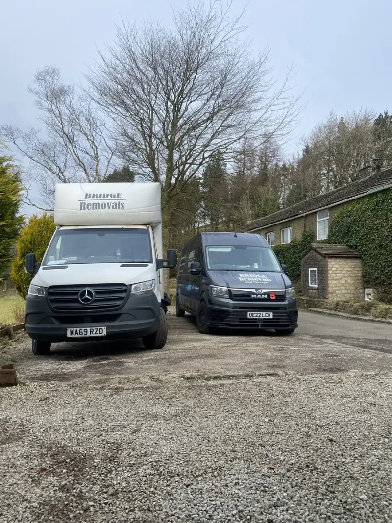 Two Bridge Removals vans on a gravel driveway in Haslingden during a house removals job.