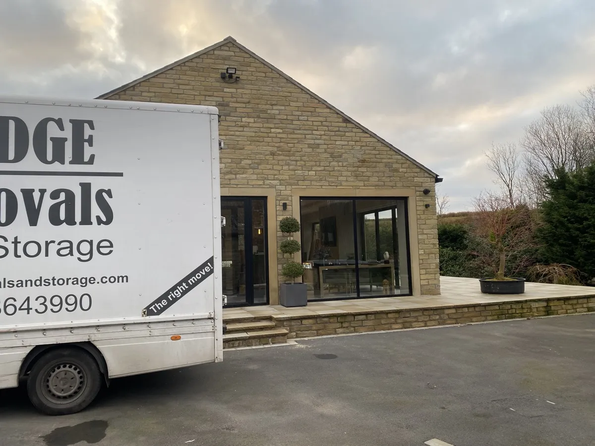 Bridge Removals van outside a stone barn-style bungalow in Edenfield, on a house removals job.