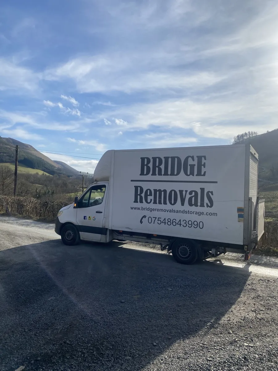 House Removals Through a Green Valley Road Bridge Removals van on a rural road through a steep green valley, on a house removals job.