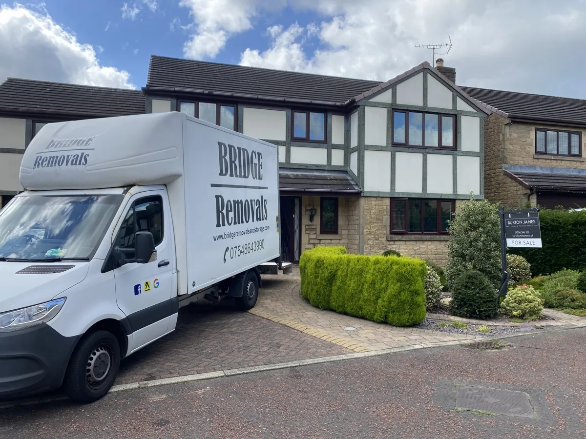Bridge Removals van on the driveway of a mock-Tudor house with topiary bushes in Waterfoot