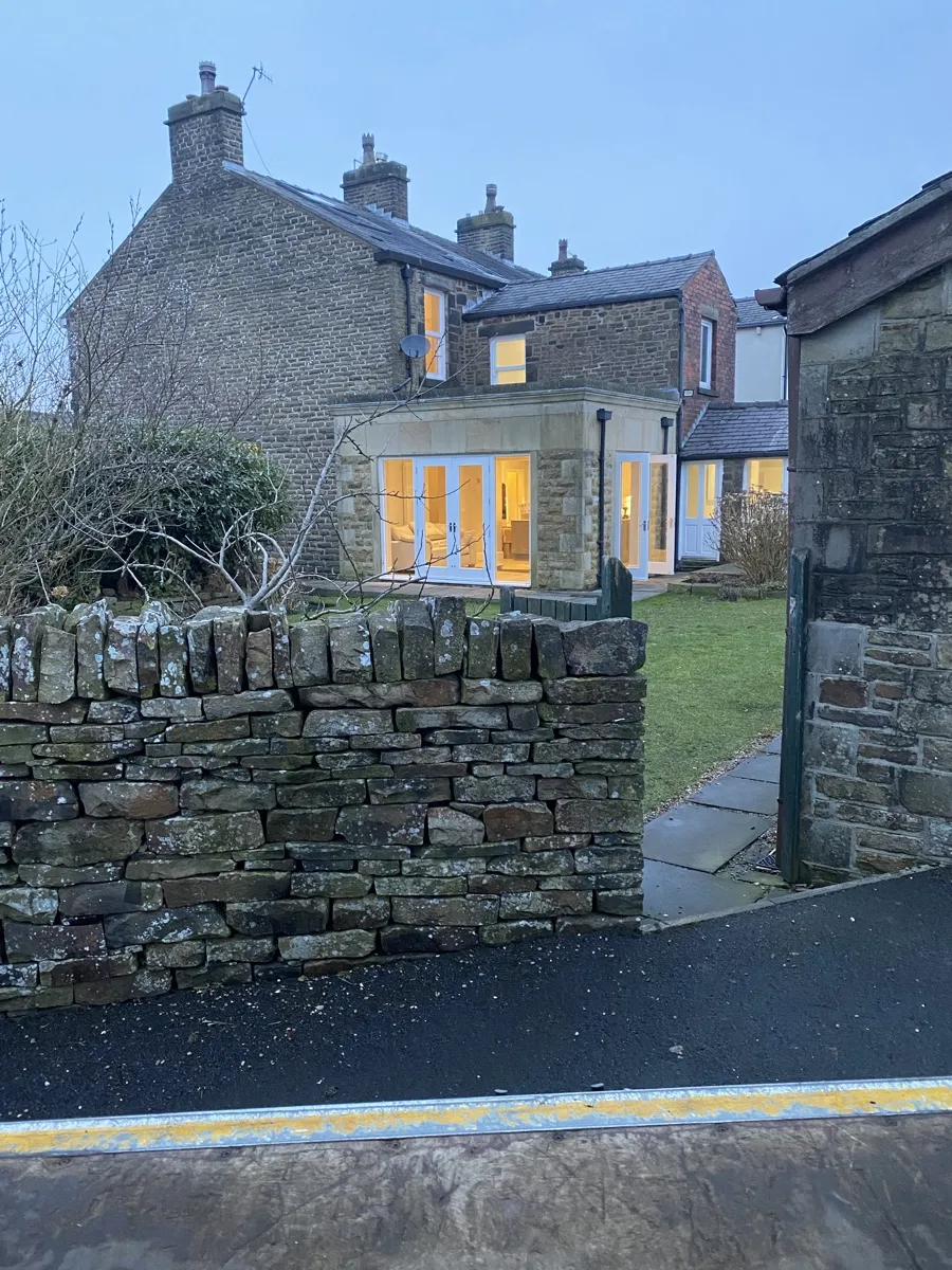 Irwell Vale Garden Clearance At Dusk Bridge Removals finishing a garden clearance job at a stone house in Irwell Vale, its windows lit at dusk.