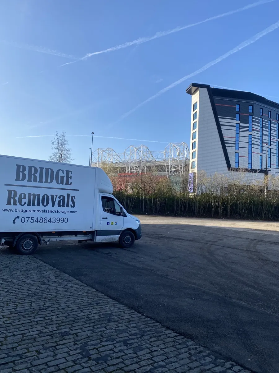 Office Removals Near Stadium Roof Trusses Bridge Removals van parked below the stadium roof trusses at Old Trafford, midway through an office removals job.