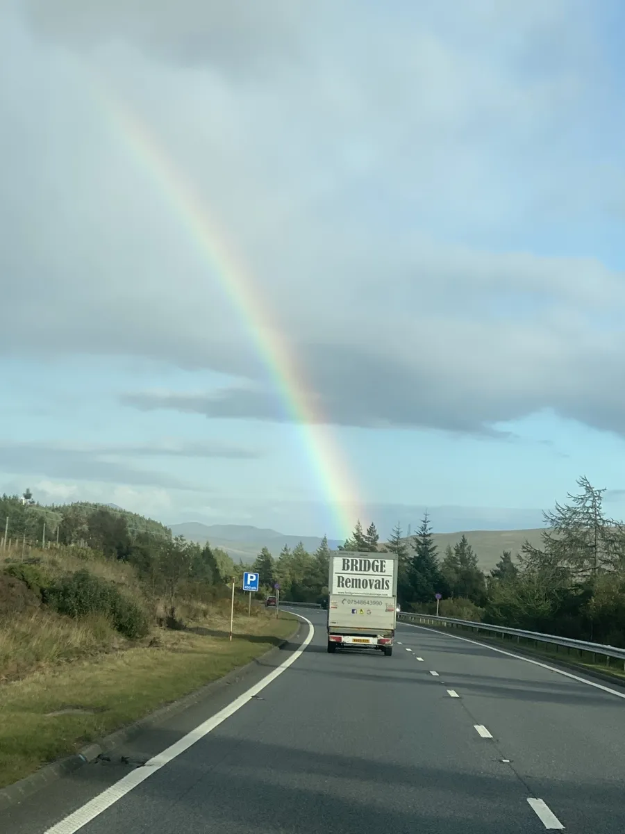 A rainbow appears to touch down on the Bridge Removals van on a rural moorland road