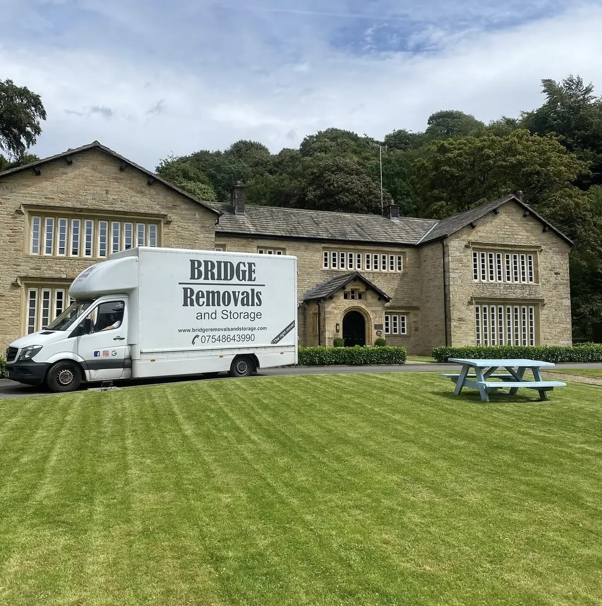 Bridge Removals van parked on the lawn of a stone manor hall, ready for a day of house removals.